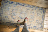 Overhead view of a distressed Oushak rug with cobalt blue vinery on an antique ivory field.