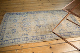 Vintage distressed Oushak rug with even wear, antique ivory, and cobalt blue floral vinery.