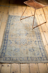 Distressed vintage Oushak rug with faded blue floral vinery and visible knot heads.