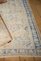 Distressed Oushak rug texture: faded cobalt blue floral vinery on antique ivory.