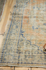 Distressed vintage Oushak rug edge showcasing faded apricot and denim blue tones.