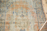 Close-up of vintage distressed Turkish Oushak rug, highlighting worn texture and apricot, ivory, denim blue.