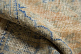 Distressed texture and hand-knotted pile of a vintage Oushak rug in apricot, beige, and denim blue.