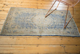 Distressed Oushak runner edge showcasing sky blue and antique ivory tones, with secured fringe.