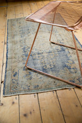 Bottom edge of a distressed vintage Oushak runner, highlighting faded blue and beige motifs.
