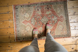 Vintage distressed Oushak rug with faded floral medallion, dusty rose, and beige colors.