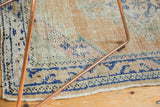 Distressed Oushak rug pile texture showing worn apricot, ivory, and cobalt blue patterns.