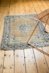 Distressed Oushak rug's fringed end, displaying its cobalt blue meandering vine border.