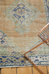 Distressed Turkish Oushak rug detail showing faded apricot field, blue patterns, and exposed foundation.