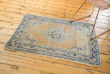 Vintage distressed Oushak rug corner, showing muted apricot field and geometric cobalt blue border.