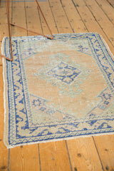Vintage Distressed Oushak rug corner with pale apricot field, cobalt blue border, fringe.