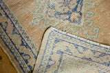 Distressed vintage Oushak rug shows hard wear to foundation, apricot, ivory, blue pile, and fringe.