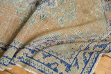 Vintage distressed Oushak rug fold, showing cobalt blue vine border and apricot hues.