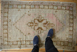 Distressed Oushak rug with stepped medallion, faded rose, beige tones, and visible knot texture.