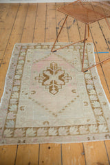 Vintage distressed Oushak rug with faded dusty rose, ivory, and pale bronze geometric patterns.