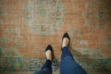 Distressed vintage Oushak carpet, showing faded pale tangerine and seafoam green designs.