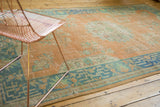 Faded tangerine and ocean blue-green distressed Oushak rug, showing even pile wear.