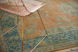 Close-up of Vintage Distressed Oushak carpet border with geometric design and faded tangerine, seafoam green, and ocean blue-green tones.