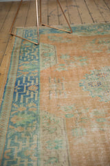 Close view of distressed Oushak carpet, faded tangerine orange, seafoam green, even wear.