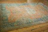 Arts & Crafts style geometric teal border and faded orange field on a distressed Oushak rug.