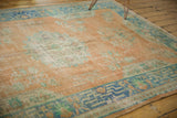 Vintage distressed Oushak rug corner: faded orange pile, blue geometric border, secured edge.