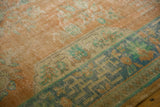 Distressed Oushak rug with faded tangerine field and worn geometric seafoam green border.