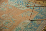 Angled detail of distressed Oushak rug, showing even pile wear with faded tangerine and seafoam tones.