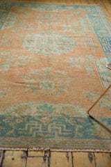 Distressed Oushak rug lower border with geometric pattern, faded orange, seafoam green, and fringe.