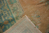 Corner of vintage Oushak rug showing worn pile texture, faint foundation, and side fringe.