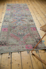 Distressed Oushak runner in muted pink, blue, and terra cotta with flowing floral patterns.