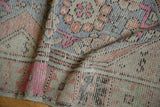 Close-up of the distressed vintage Oushak runner's faded pile texture and vibrant pink highlights.