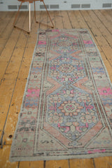 Distressed Oushak rug runner with faded pink, blue, terra cotta floral border detail.