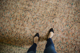 Distressed Oushak carpet with pale apricot peach and mint green scrolling vinery.