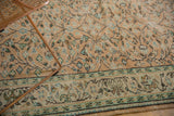 Close-up of distressed Oushak's pale mint border with apricot peach scrolling vinery.