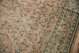 Worn pale apricot field and mint green scrolling vinery detail on distressed Oushak rug.