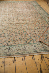 Distressed vintage Oushak rug with faded apricot vinery, mint accents, and visible foundation wear.