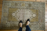 Close-up of a distressed Melas rug, showing worn pile, germinating floral and seed motif.