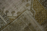 Corner of vintage distressed Melas rug, showing worn pile, seed motif, and faint foundation.
