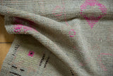 Distressed Oushak rug texture with bright pink geometric motifs and worn pile.