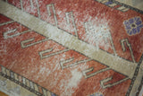 Rust and ivory distressed Oushak rug detail, showcasing worn texture and a lavender bloom.