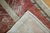 Distressed vintage Oushak rug corner showing rust pile, ivory field, and hand-knotted reverse.