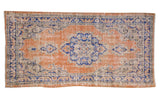 Distressed vintage Oushak rug runner, orange rust field with denim blue scalloped medallion.