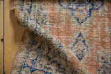 Distressed Oushak rug runner's soft pile texture, featuring pale orange rust and deep blue hues.