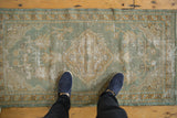 Vintage distressed Oushak rug corner, highlighting seafoam green, beige vinery, and worn pile.