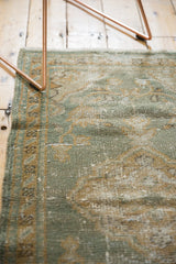 Distressed vintage Oushak rug pile with seafoam green and beige floral vinery, showing mostly even wear.