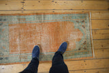 Distressed tangerine orange Oushak runner's border and corner floral blossom detail.