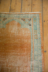 Close-up of distressed pale tangerine Oushak field with seafoam green floral border.