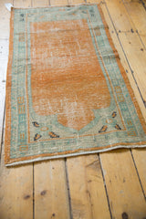 Distressed vintage Oushak runner corner with even wear, pale tangerine, and seafoam green border.