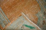 Distressed tangerine orange pile, seafoam green border, and secured side edge of Oushak runner.