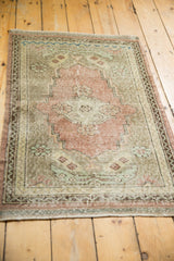 Distressed Oushak rug with dusty rose, beige, and mint green motifs and even wear.